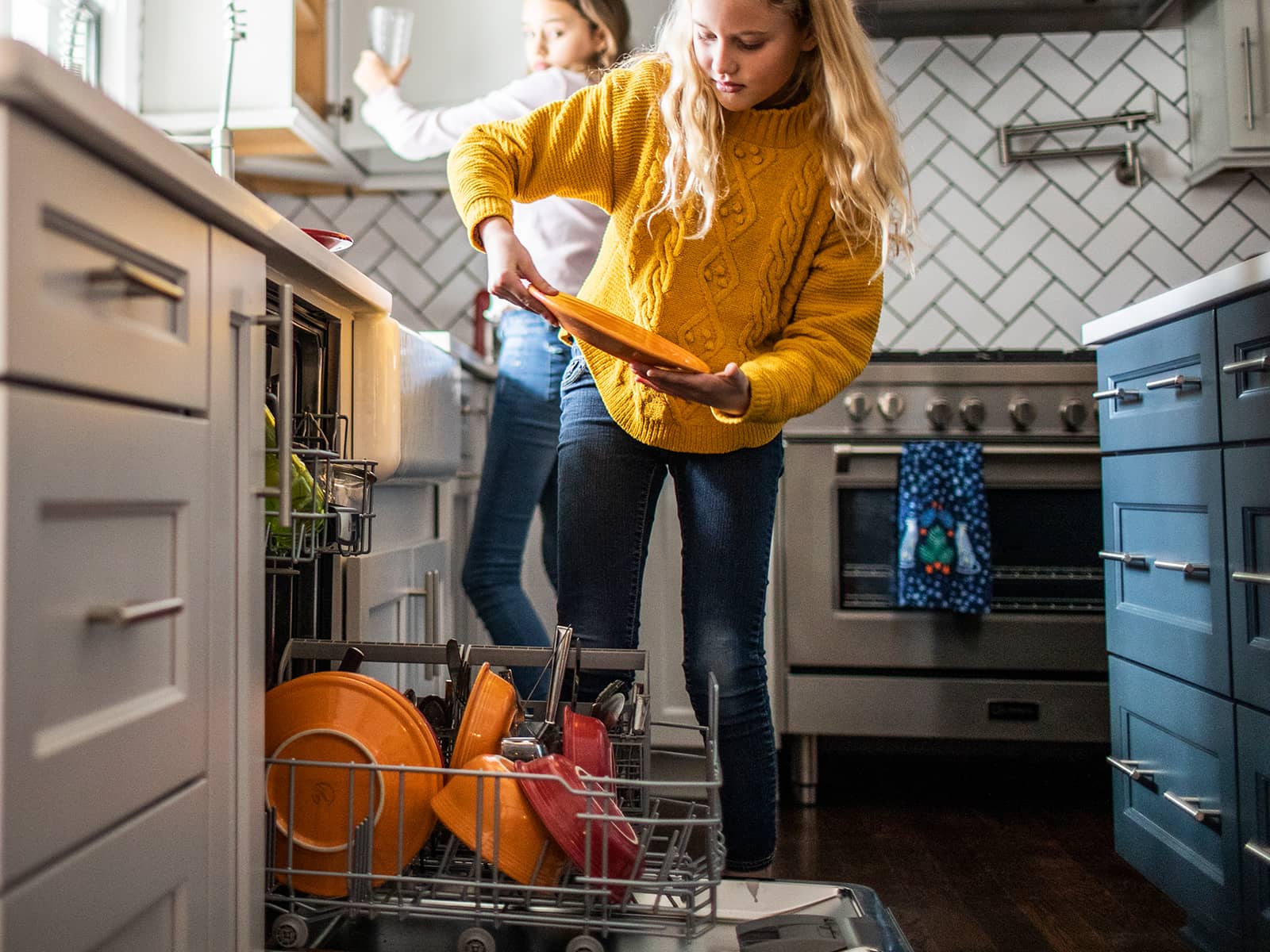 Pige fylder tallerkner i en opvaskemaskine. Hvor meget strøm  bruger en opvaskemaskine?