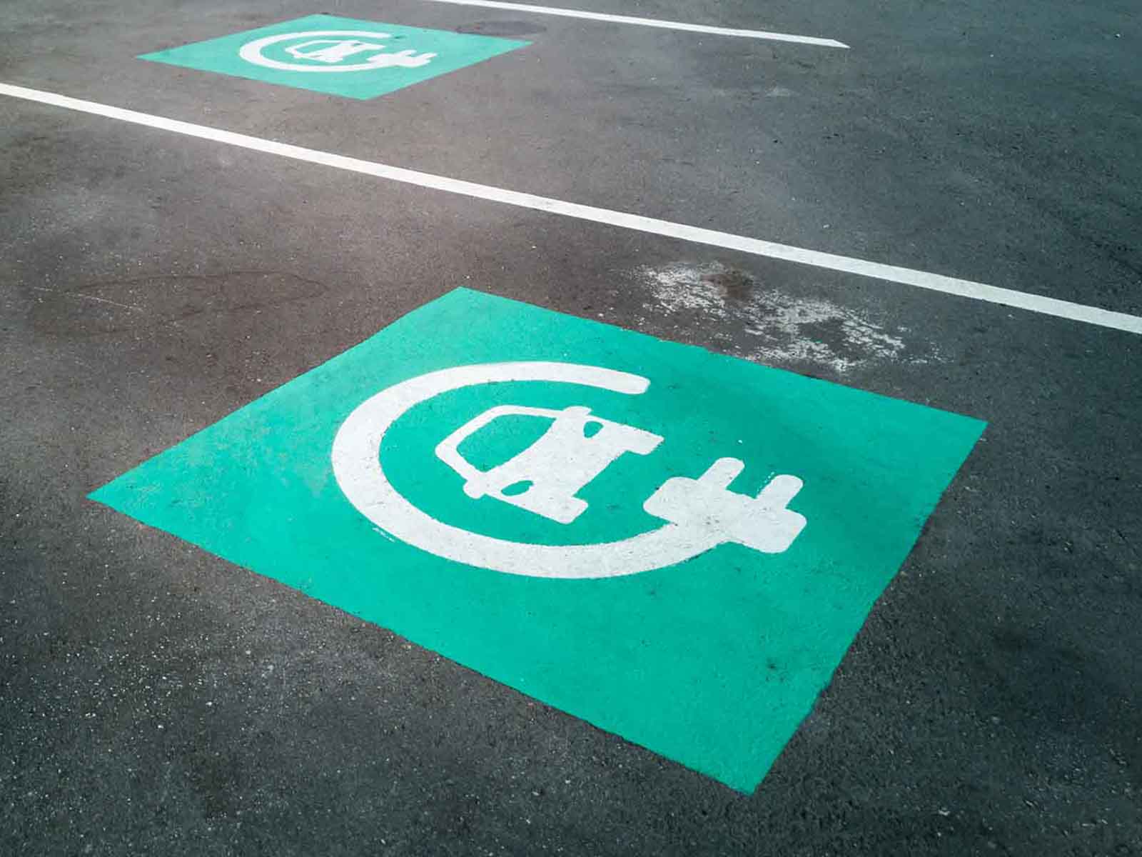 Elbil ikon på asfalt. Må man holde på elbilpladser uden at lade? Vi undersøger det.